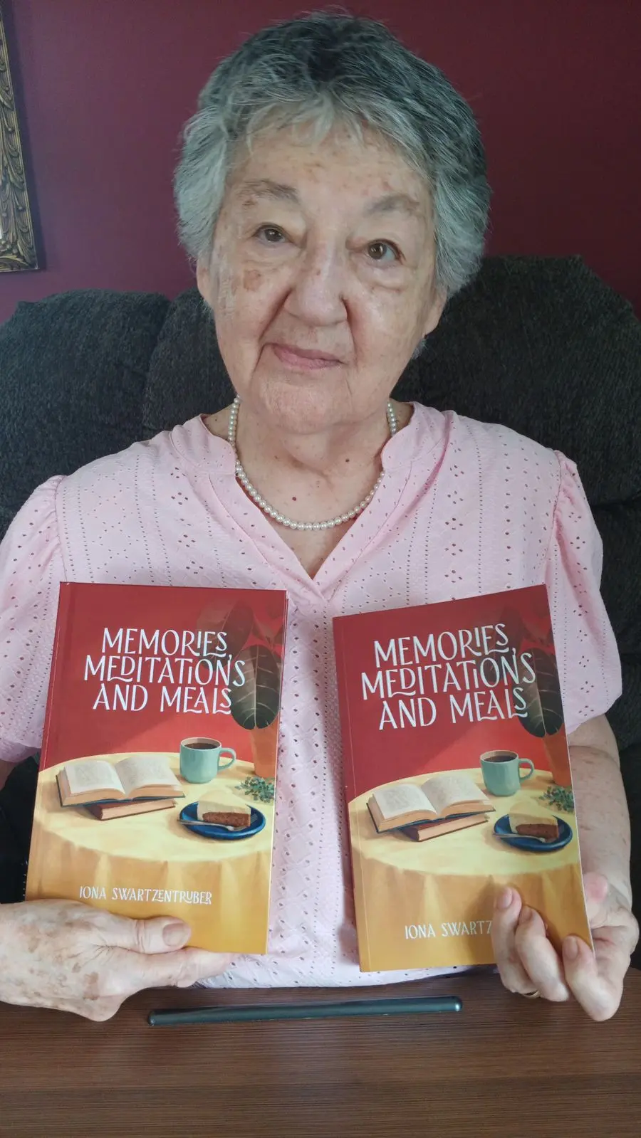 An author holding two copies of Memories, Meditations and Meals